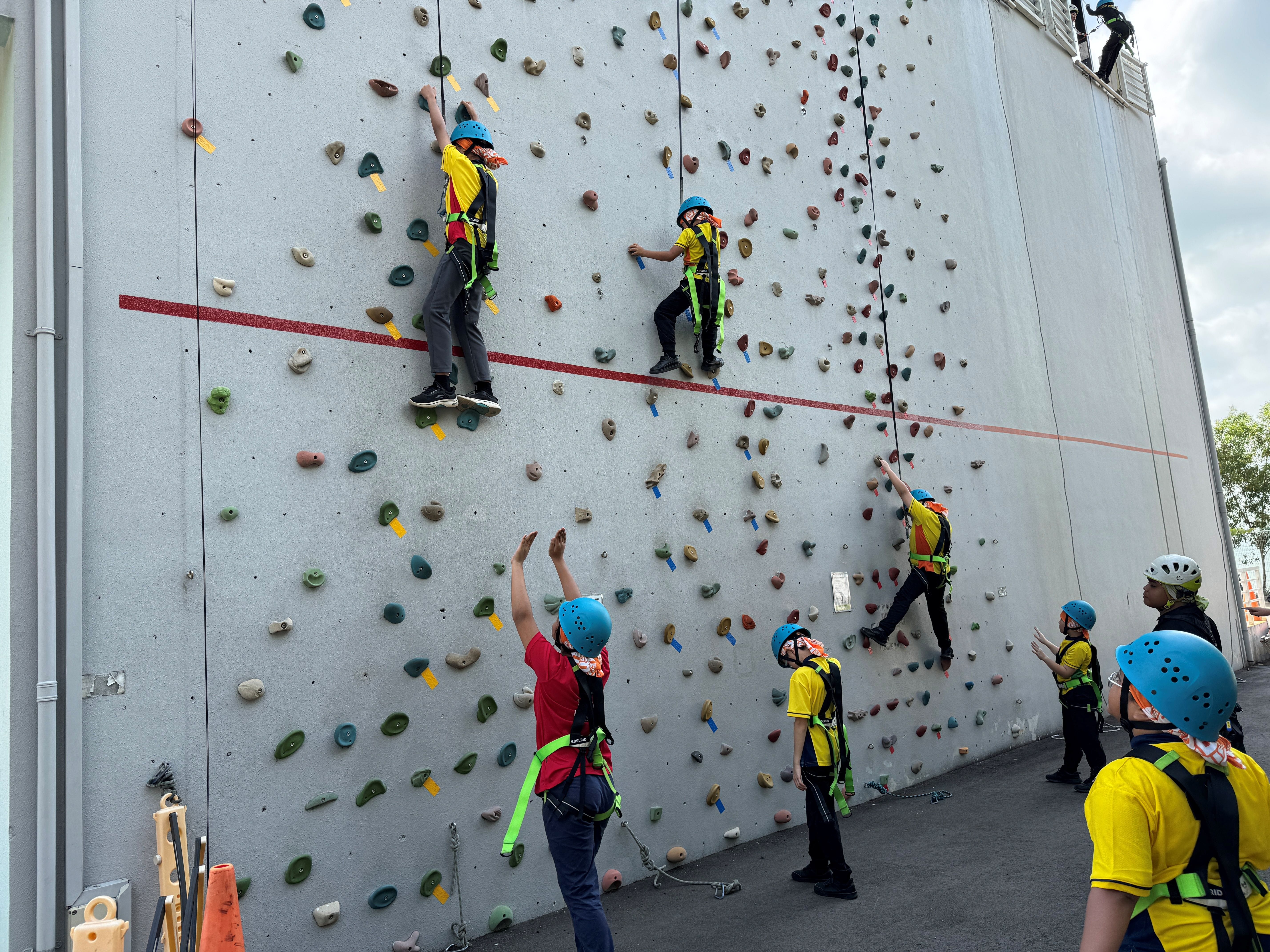 Students supporting each other during rock climbing with the instructors looking out for them